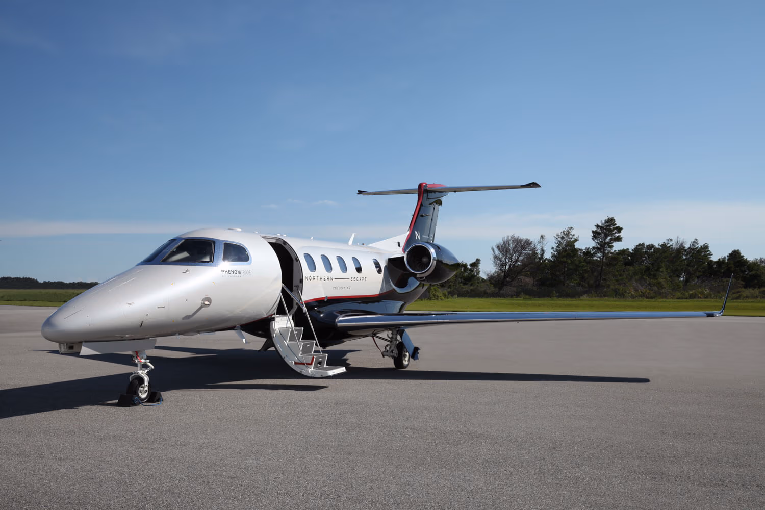 An Embraer Phenom 300E light jet at rest on a private apron