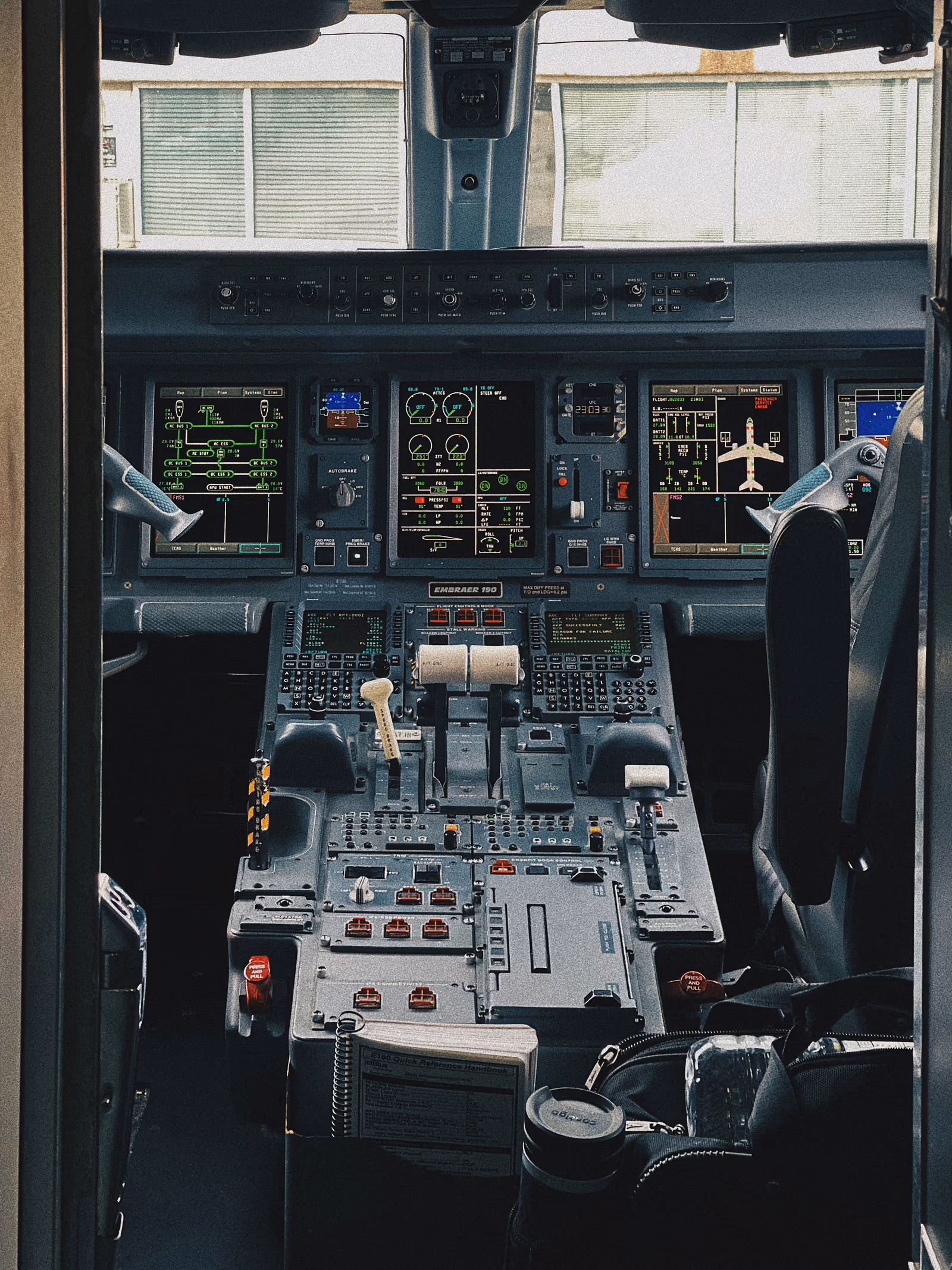A modern business-jet flight deck with all primary displays powered on, headsets resting, the room ready